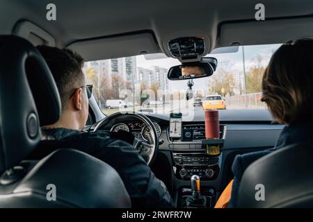 A couple, a man and a woman are traveling in a car in the city. The holders are equipped with a mobile phone with a navigation app and a reusable Stock Photo