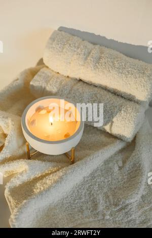 White towels and a burning scented candle in a bowl. Close-up view. SPA procedures. Stock Photo