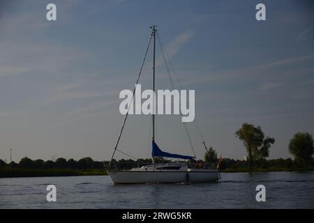A sailing ship passing through the canal in typical Dutch landscape Stock Photo