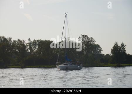 A sailing ship passing through the canal in typical Dutch landscape Stock Photo