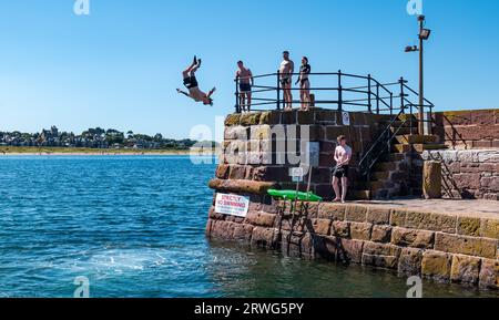 Boy somersaulting into sea from quayside in hot Summer weather, North Berwick harbour, East Lothian, Scotland, UK Stock Photo