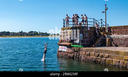 Boy diving into sea from quayside in hot Summer weather, North Berwick harbour, East Lothian, Scotland, UK Stock Photo