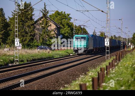 An electrified freight train passing through a rural landscape in Germany Stock Photo