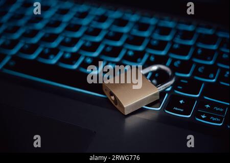 Golden locked padlock lying on a black laptop computer keyboard in a conceptual image of cyber security, firewall and data and passwork protection. Stock Photo