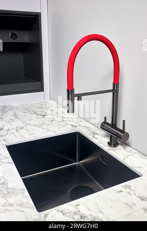 Compact undermount square stainless steel sink with red tap in contemporary style. Water faucet sink built in compact high pressure laminate HPL Stock Photo
