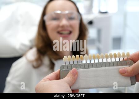 tooth whitening, perfect white crown teeth close up with shade guide bleach color, female veneer smile, dental care and stomatology, dentistry, copyspace. Stock Photo