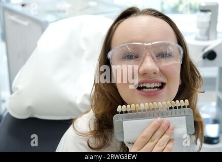 tooth whitening, perfect white crown teeth close up with shade guide bleach color, female veneer smile, dental care and stomatology, dentistry, copyspace. Stock Photo