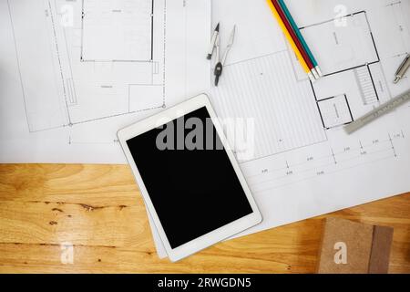 Construction blueprints with tools and tablet, top view. Tablet with architectural blueprints and measuring tools on wooden table. Stock Photo