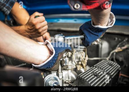 Two Caucasian Professional Car Mechanics Performing Gasoline Engine Repair Stock Photo