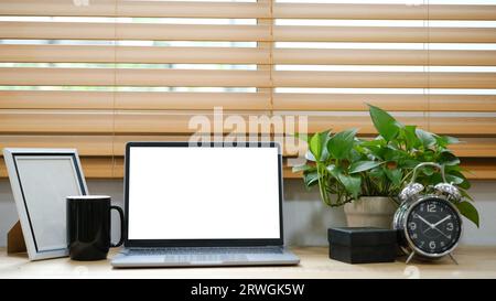 White laptop with blank screen placed on table near window. Stock Photo