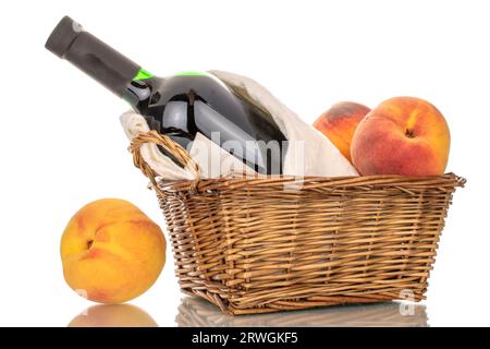 One bottle of red wine, several ripe peaches in a basket, macro, isolated on white background. Stock Photo