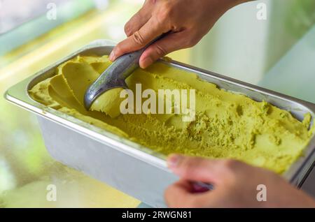 hand scooping a scoop of Avocado ice cream into a spoon in fridge Stock Photo