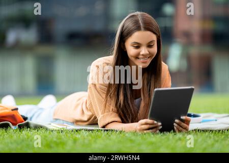 Relaxed young woman student lying on grass with digital tablet Stock Photo