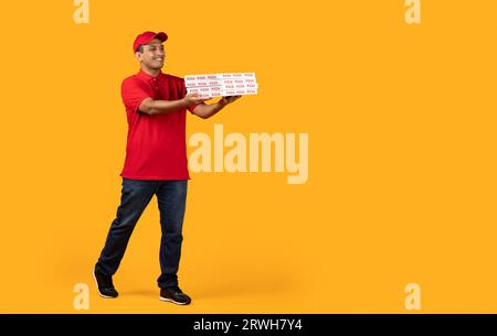 Middle Eastern Courier Holds Stack Of Pizzas Boxes, Yellow Background Stock Photo