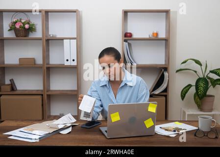 female accountant at home. calculating finances, using calculator. Managing freelance income taxes Stock Photo