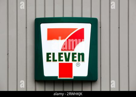 7-Eleven logo on a wall. 7-Eleven is an international chain of convenience stores that operates primarily as a franchise Stock Photo