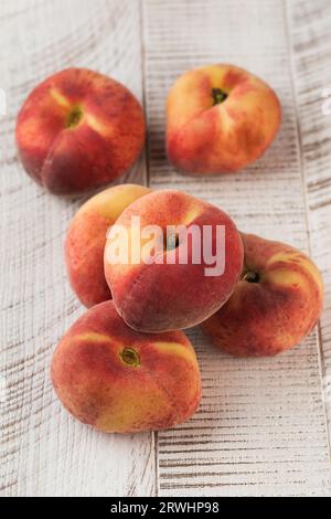 Juicy ripe flat peaches on a white wooden background. Healthy eating, fruits. Stock Photo