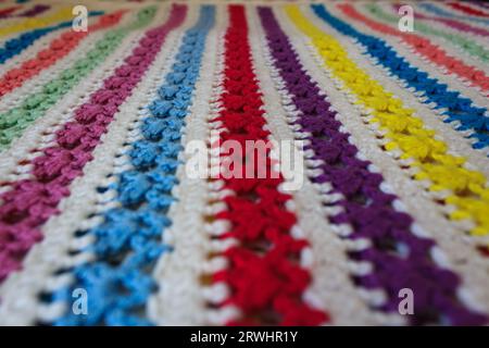 Background crocheted fabric, pattern of multi-colored rows handmade. Stock Photo