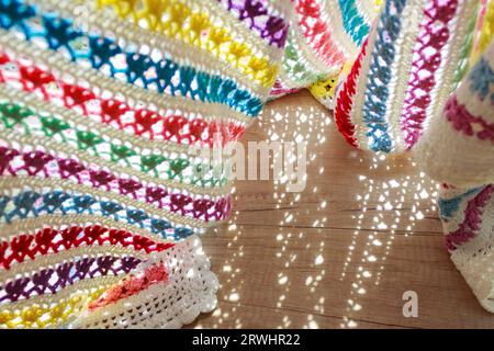 Knitted striped plaid in a bright color. Shadow pattern from a lace plaid on a wooden surface. Stock Photo