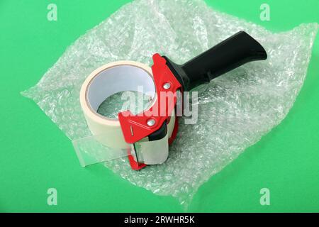 Packing tape dispenser and bubble wrap on green background Stock Photo