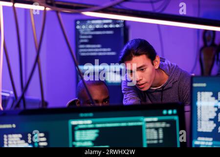 Criminals hacking into computer system while planning cyberattack and discussing phishing technique. Hackers doing ddos attack to break website and running malware code on screen Stock Photo
