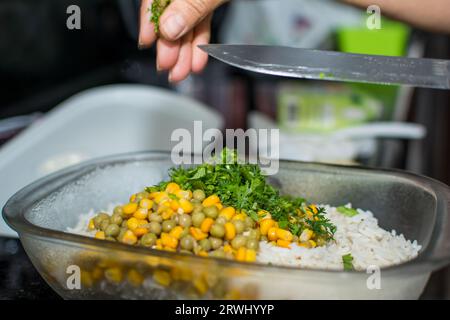 Salad with peas, corn and coriander being prepared in a glass bowl. Healthy food. Stock Photo