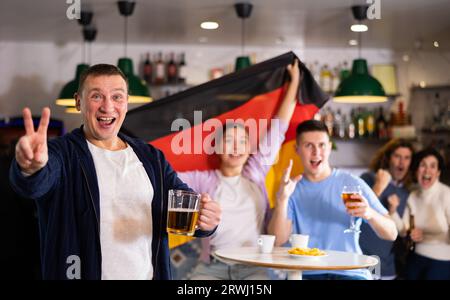 Man and woman with Germany flag drinking alcohol and having conversation on party in nightclub Stock Photo