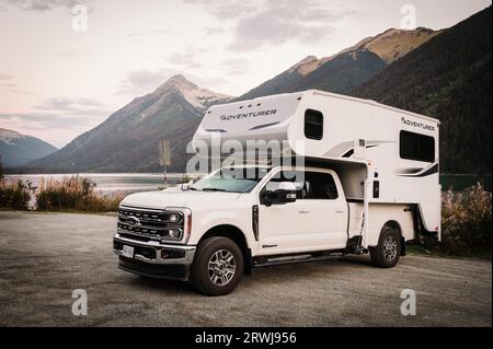 A pick-up truck camper parked on the shore of Duffy Lake. Stock Photo