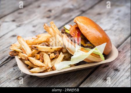 A take away bacon cheese burger with fresh fries.  Served in a compostable paper tray. Stock Photo