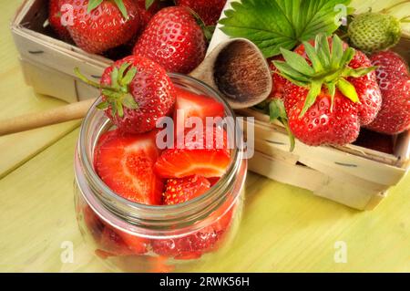 Strawberries in basket and jar next to cooking spoon Stock Photo