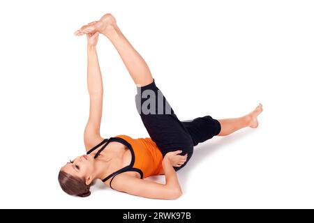 Woman doing Reclining Big Toe yoga pose (there are four versions of this exercise), sanskrit name: Supta Padangusthasana, this pose stretches the Stock Photo