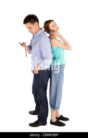 Young casual full body couple on the phone standing back to back, man reading message, upset woman getting bad news, isolated on white background Stock Photo