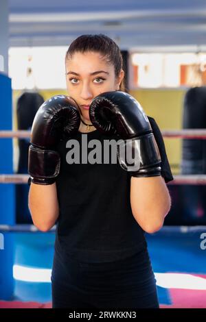 Female boxer portrait in guard position in a boxing ring. Fighting sport training gym. Stock Photo