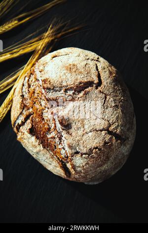 Freshly baked traditional bread on a black board. Yeast-free rye bread, close-up. Food background. Stock Photo
