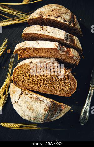 Freshly baked traditional bread on a black board. Sliced rye bread, close-up. Food background. Stock Photo