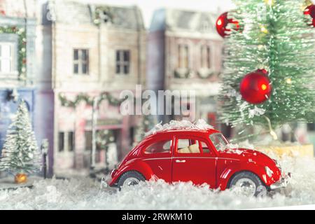 Red retro toy car. Winter snowy European street decorated for Christmas. Homemade decorated toy houses. Selective focus. St. Petersburg, Russia - Nove Stock Photo