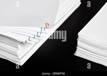 Stacks of papers with multicolored paper clips on a dark background Stock Photo