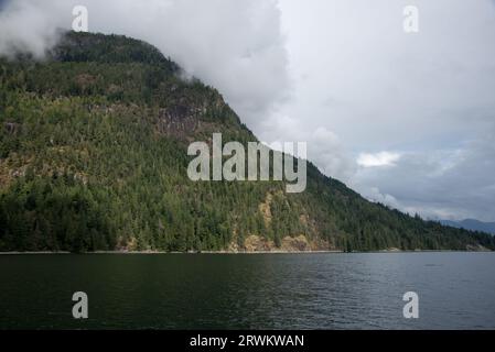 Lush rainforest is covering the calm waters of Inland Passage between the east coast of Vancouver Island and the Canadian mainland. Stock Photo