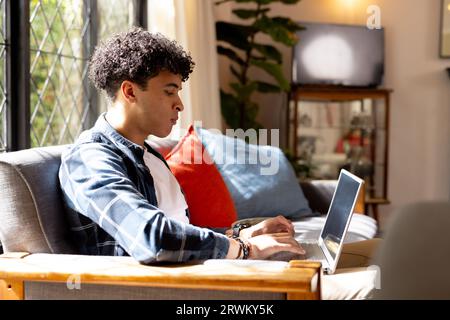 Focused biracial man working at home and working with laptop Stock Photo