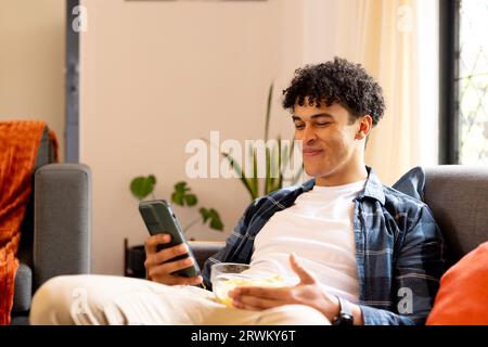 Happy biracial man sitting at home and working with tablet Stock Photo