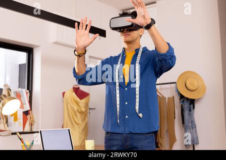 Focused biracial male fashion designer using vr glasses in studio Stock Photo