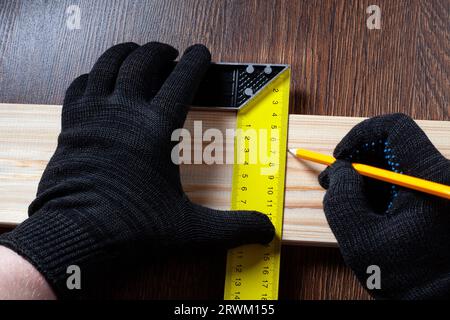 carpenter using Square ruler and pencil for measuring on wooden board. construction concept Stock Photo
