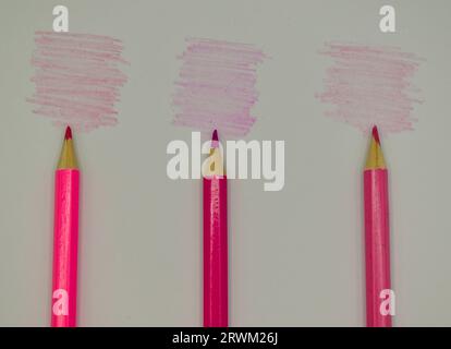 Three pink coloured pencils placed on white card next to their respective colour shades. Stock Photo