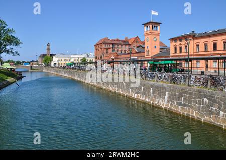 Central Station in Malmo, Sweden, alongside Ostra Hamnkanalen canal, with Swedish flags and a large number of bicycles. Transport links Stock Photo