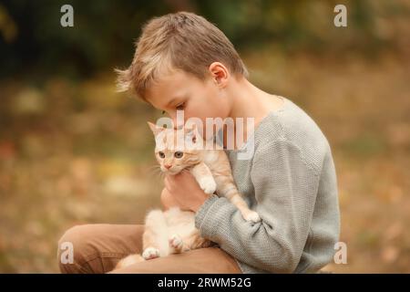 Kid with ginger cat on a autumn background.  Stock Photo