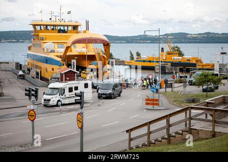 The ferry between Gränna and Visingsö has arrived at the island's harbor, and cars and passengers are disembarking from the boat Stock Photo