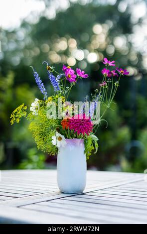 the natural elegance of a stunning bouquet of wild summer flowers from Sweden. The vibrant blooms are gracefully arranged in a vase on a table, with t Stock Photo