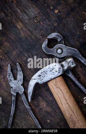 Old pliers, hammer and pincers on an old wooden workbench. Old work tools Stock Photo