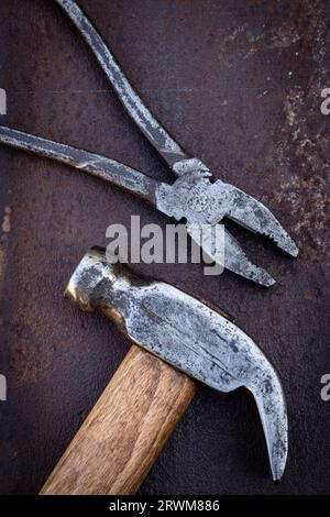 Old hammer and pliers on an iron rusty background Stock Photo