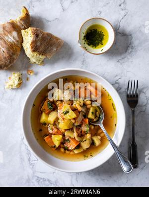 top-down image showcases a visually pleasing and wholesome vegetarian soup. The soup features chunks of potatoes, onions, carrots, white beans, turnip Stock Photo